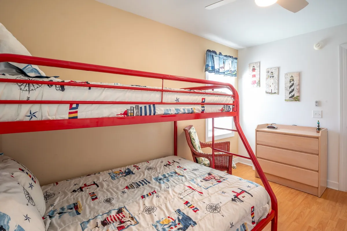 A cheerful and cozy kids' room featuring bright bunk beds, decorative wall art, and a wooden dresser. The playful design signals a family-friendly atmosphere and a perfect spot for children to recharge after a day of sun and adventure.